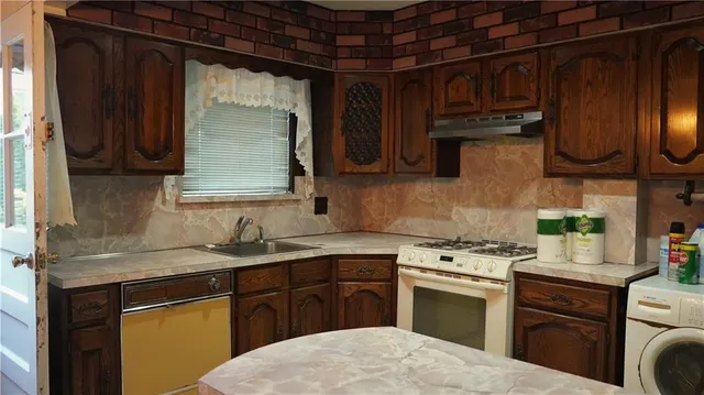 a kitchen with a sink dishwasher a stove and a microwave oven with cabinets