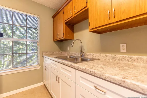 a bathroom with a granite countertop sink and a window