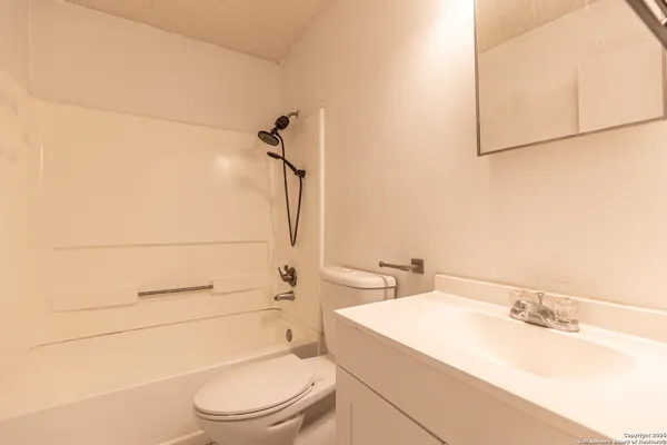 a bathroom with a granite countertop toilet sink and mirror