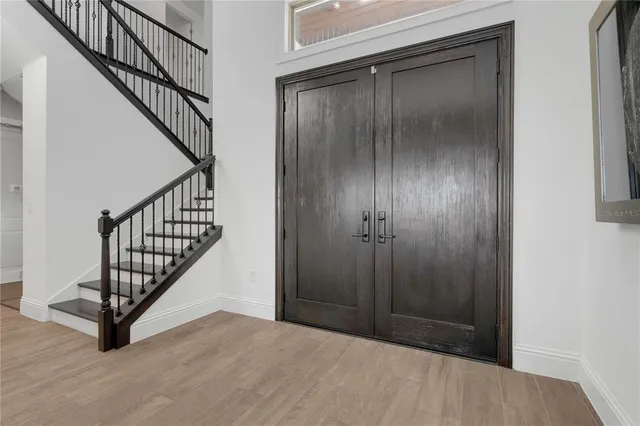 a living room with furniture a dining table wooden floor and a large window