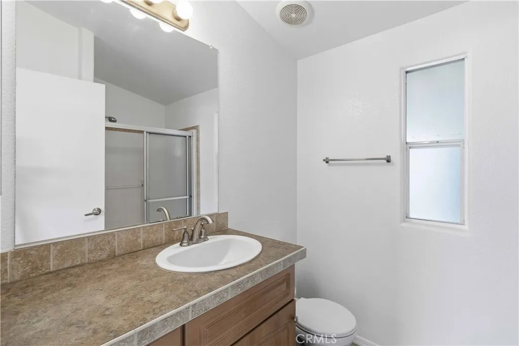 1550 Rory Simi Valley, Unit 133 Simi Valley, CA 93063 - Photo 16 of 29 a bathroom with a granite countertop sink toilet a mirror and a vanity