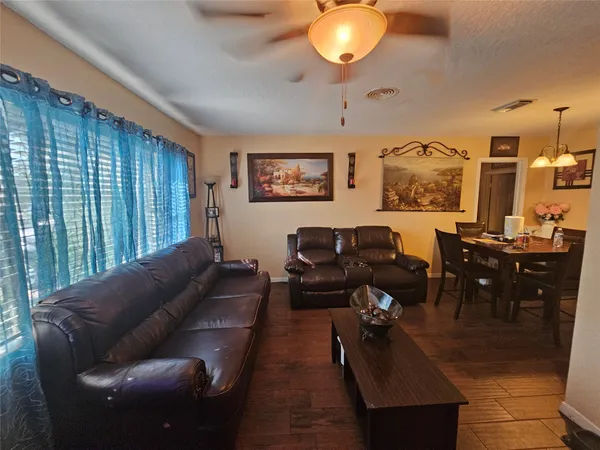 a living room with furniture potted plant and open kitchen view