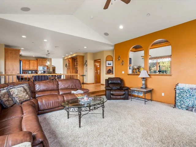 a living room with furniture kitchen view and a large window