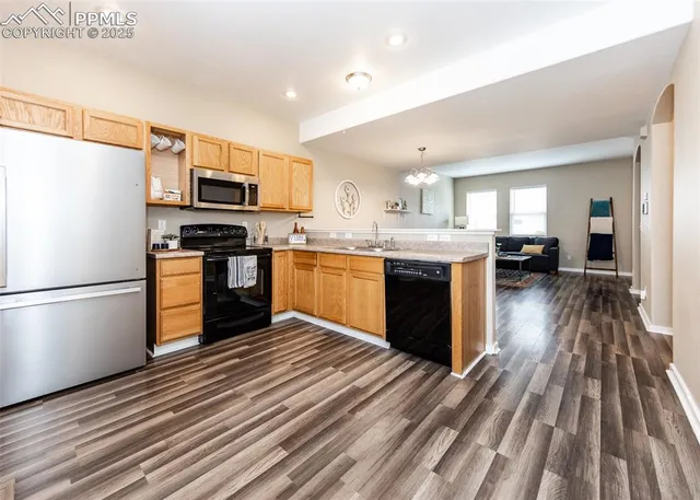 a kitchen with stainless steel appliances granite countertop a refrigerator a stove top oven a sink dishwasher and white cabinets with wooden floor