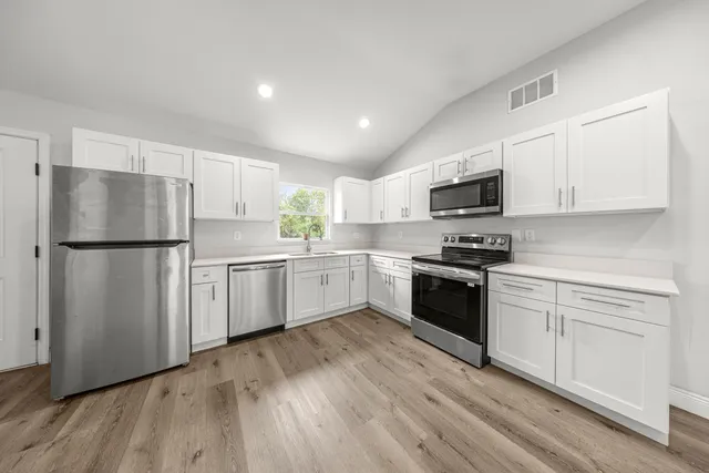 a kitchen with white cabinets stainless steel appliances and a refrigerator