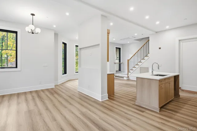 a large white kitchen with wooden floor and stainless steel appliances