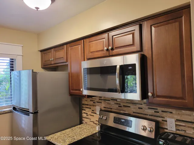a kitchen with stainless steel appliances granite countertop a refrigerator and a stove top oven