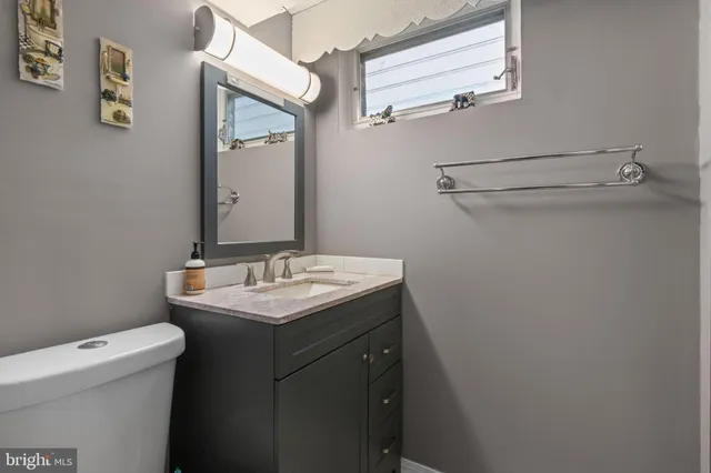 a bathroom with a granite countertop sink and a toilet