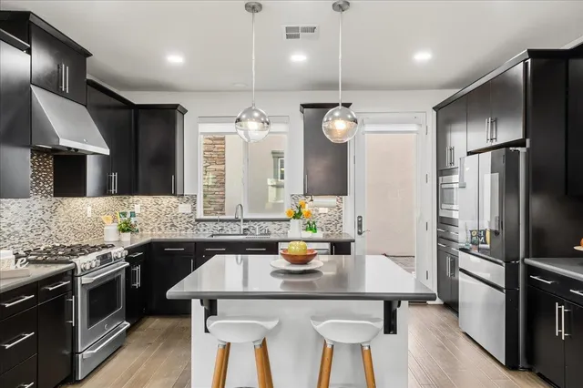 a kitchen with stainless steel appliances kitchen island granite countertop a sink stove and refrigerator