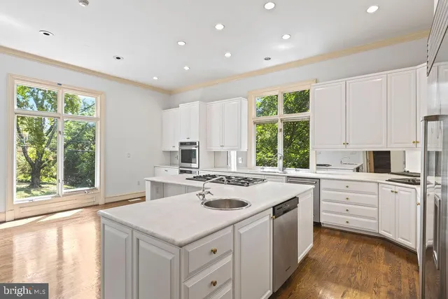 a kitchen with stainless steel appliances kitchen island granite countertop a stove a sink and white cabinets