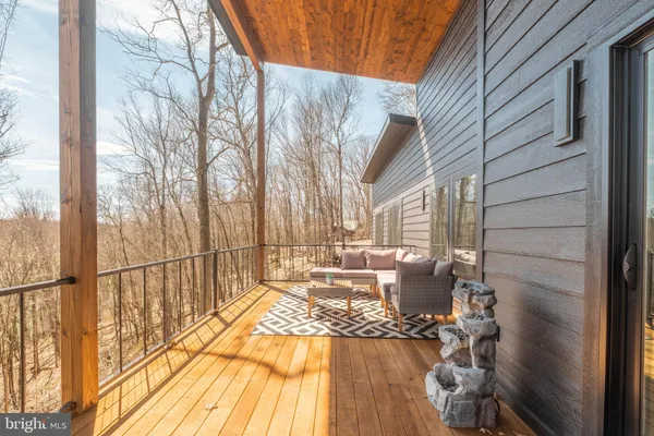 a view of a patio with table and chairs and couches with wooden floor and fence