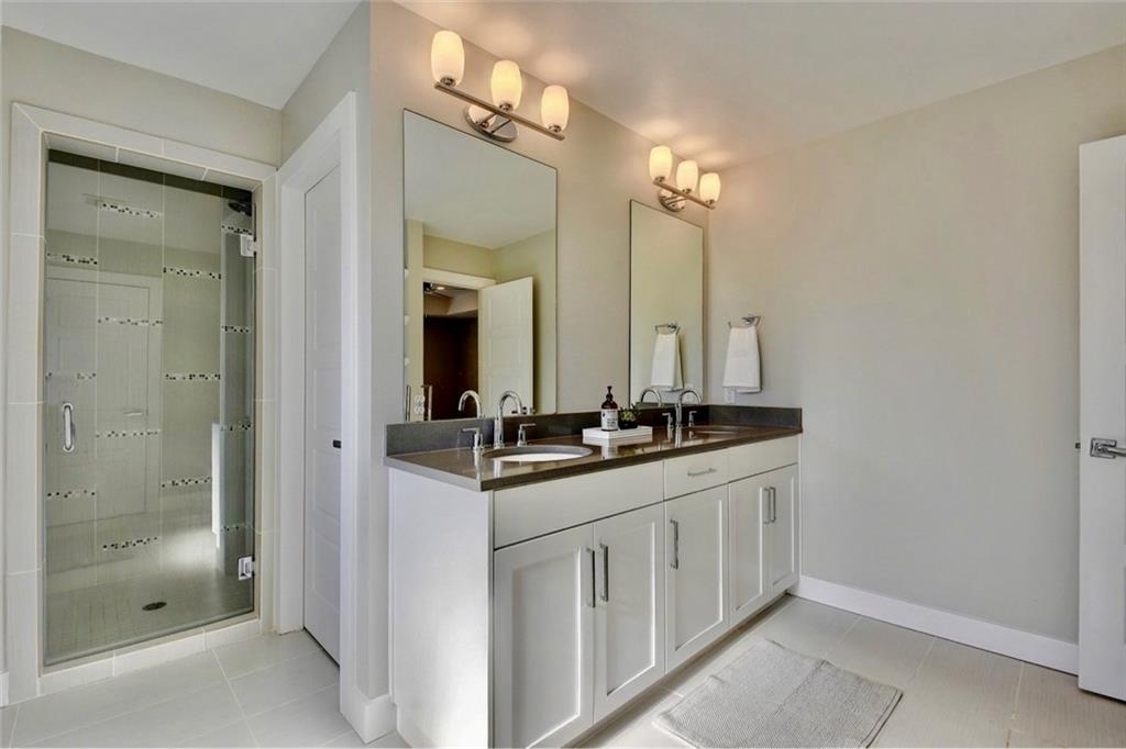 701 East 49th Street, Unit B Austin, TX 78751 - Photo 16 of 27 Bathroom with double vanity, light tile patterned flooring, and a stall shower