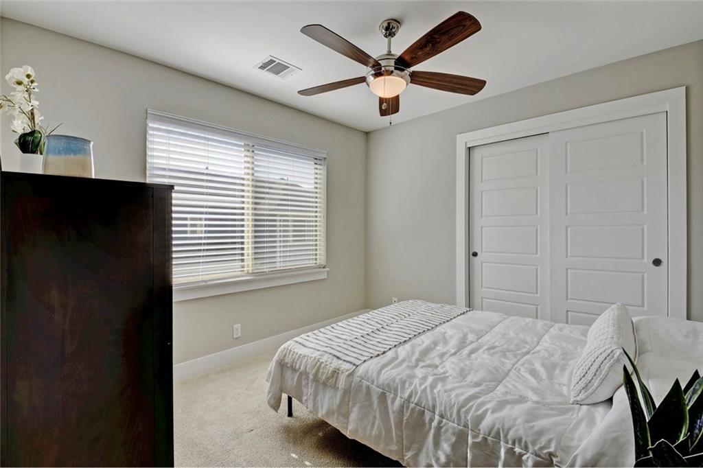 701 East 49th Street, Unit B Austin, TX 78751 - Photo 19 of 27 Bedroom with light colored carpet, a closet, and a ceiling fan