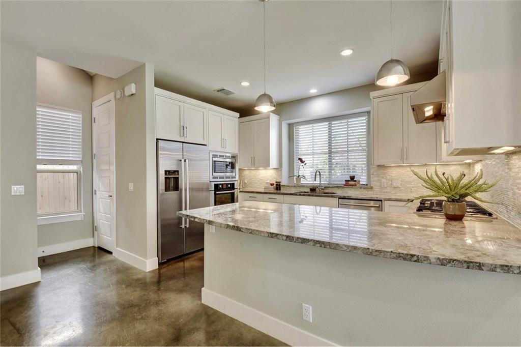 701 East 49th Street, Unit B Austin, TX 78751 - Photo 4 of 27 Kitchen featuring light stone countertops, built in appliances, concrete flooring, and white cabinets