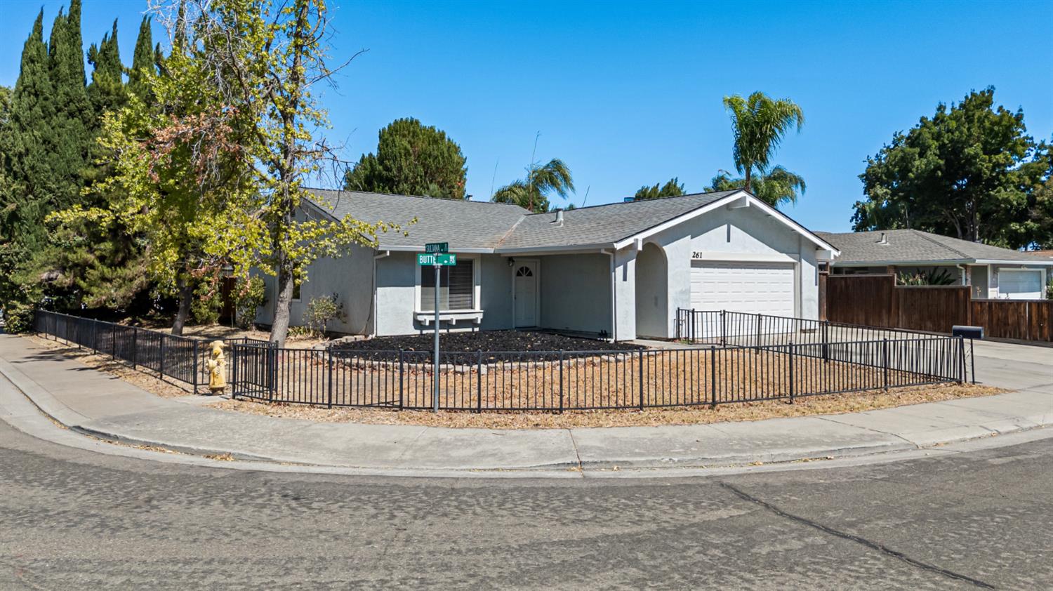a view of a white house with a small yard and large tree