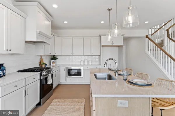 a kitchen with kitchen island granite countertop a stove a sink dishwasher and white cabinets with wooden floor
