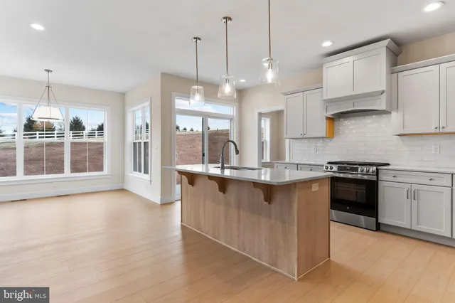 a kitchen with stainless steel appliances granite countertop a stove a sink and a granite counter tops with white cabinets