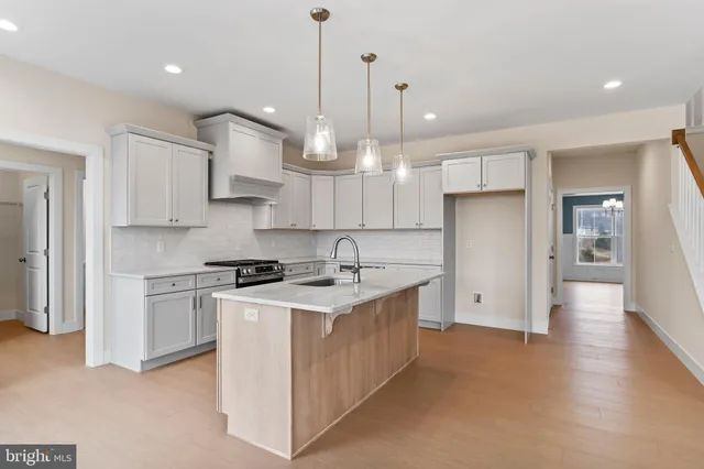 a kitchen with stainless steel appliances granite countertop a sink a stove a refrigerator and white cabinets