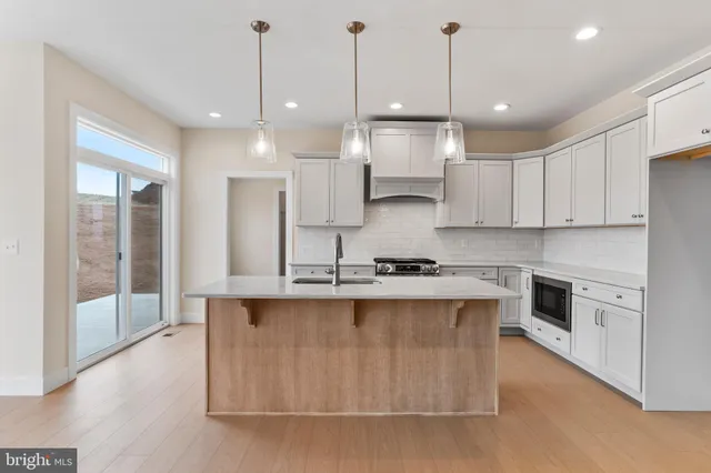 a large kitchen with kitchen island a stove a sink a center island and a wooden floor