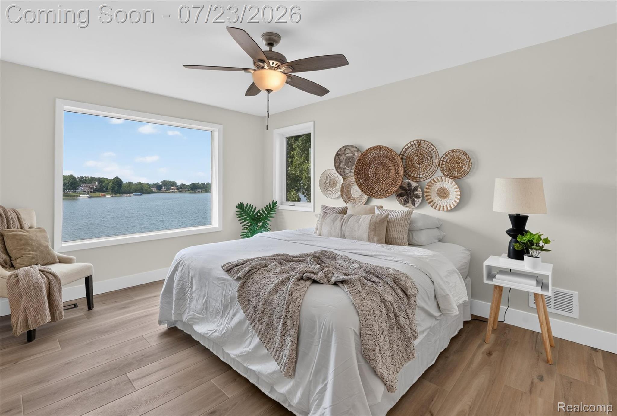 3429 Rolston Road Fenton, MI 48430 - Photo 15 of 62 Expansive window overlooking the lake, complemented by wood-finish flooring, a ceiling fan with integrated lighting, and neutral wall tones