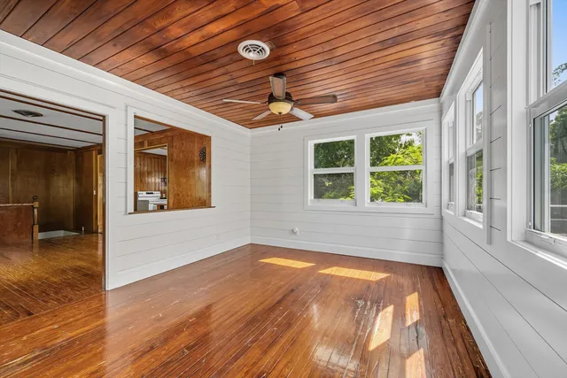 a view of an empty room with a window and wooden floor