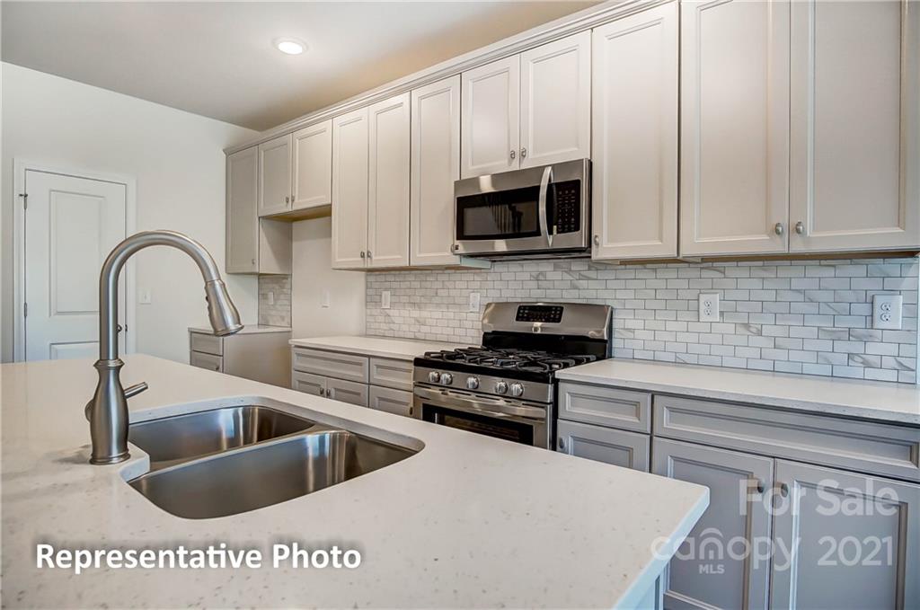 2153 Bexar Trail Matthews, NC 28105 - Photo 19 of 35 a kitchen with stainless steel appliances a sink a stove and white cabinets