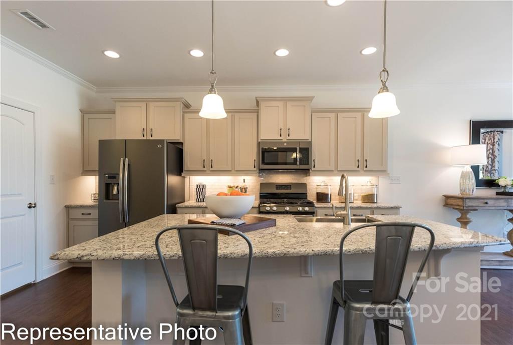 2153 Bexar Trail Matthews, NC 28105 - Photo 21 of 35 a kitchen with stainless steel appliances a dining table chairs refrigerator and cabinets