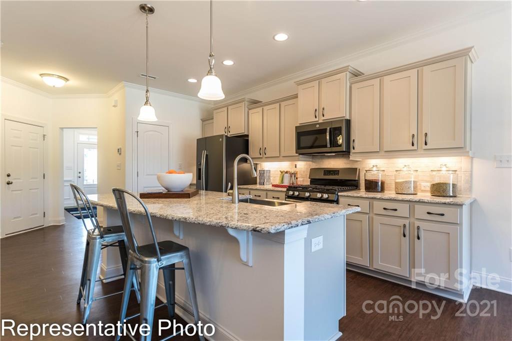 2153 Bexar Trail Matthews, NC 28105 - Photo 22 of 35 a kitchen with stainless steel appliances granite countertop a stove top oven a sink a stove a dining table and chairs