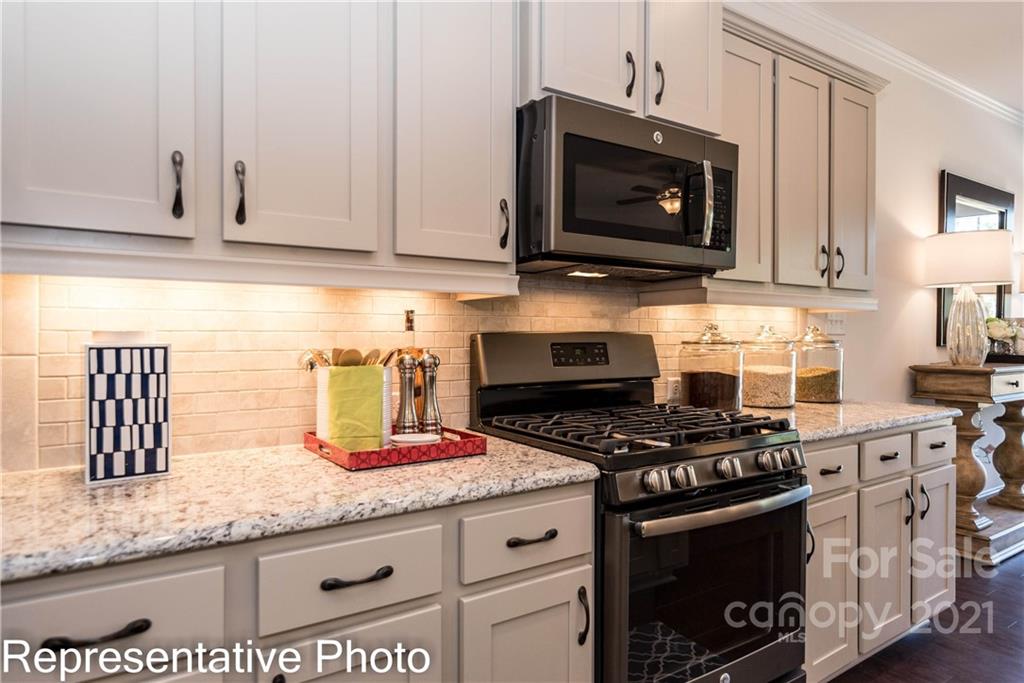 2153 Bexar Trail Matthews, NC 28105 - Photo 24 of 35 a kitchen with granite countertop a stove a microwave a sink and cabinets