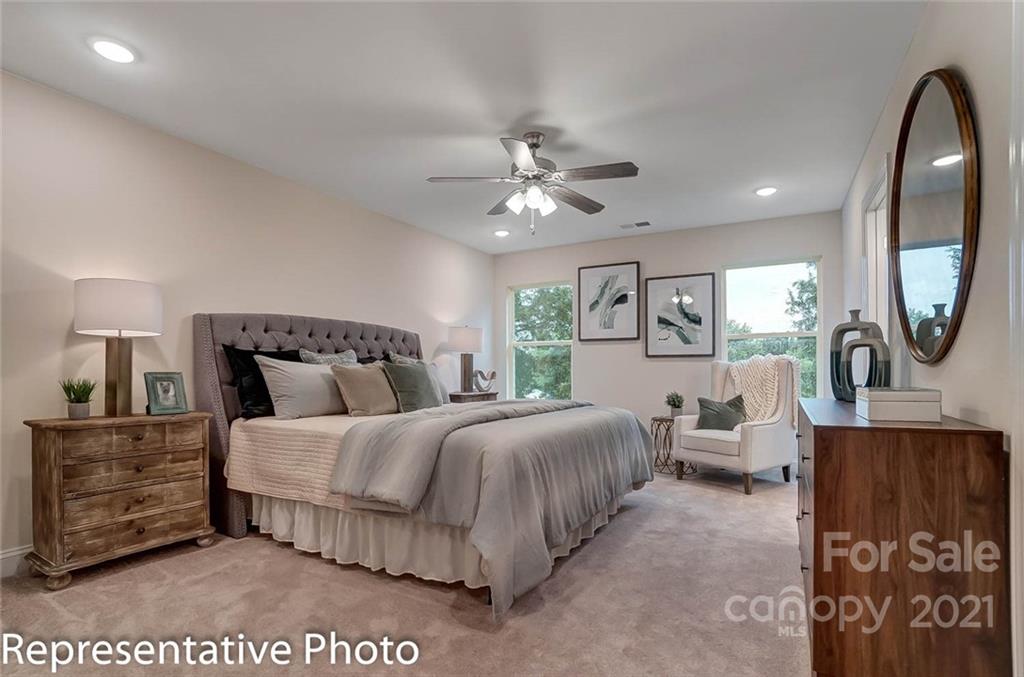 2153 Bexar Trail Matthews, NC 28105 - Photo 26 of 35 a spacious bedroom with a bed a mirror on dresser and a chandelier