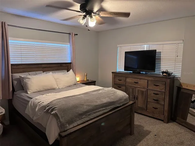 a bedroom with a bed and a flat tv screen on dresser