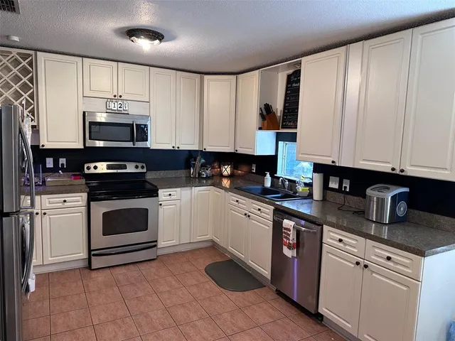 a kitchen with granite countertop white cabinets white stainless steel appliances and a sink