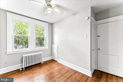 an empty room with wooden floor fan and windows