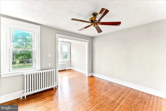 an empty room with wooden floor fan and windows