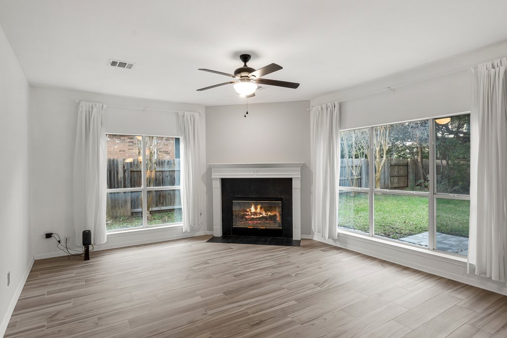 1406 Dapplegrey Lane Austin, TX 78727 - Photo 10 of 38 Unfurnished living room featuring a ceiling fan, a tile fireplace, and light wood-style floors