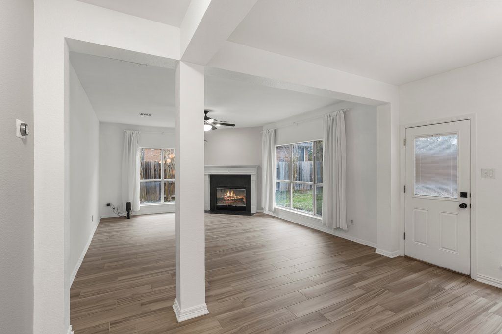 1406 Dapplegrey Lane Austin, TX 78727 - Photo 11 of 38 Unfurnished living room with a fireplace with flush hearth, light wood finished floors, and ceiling fan