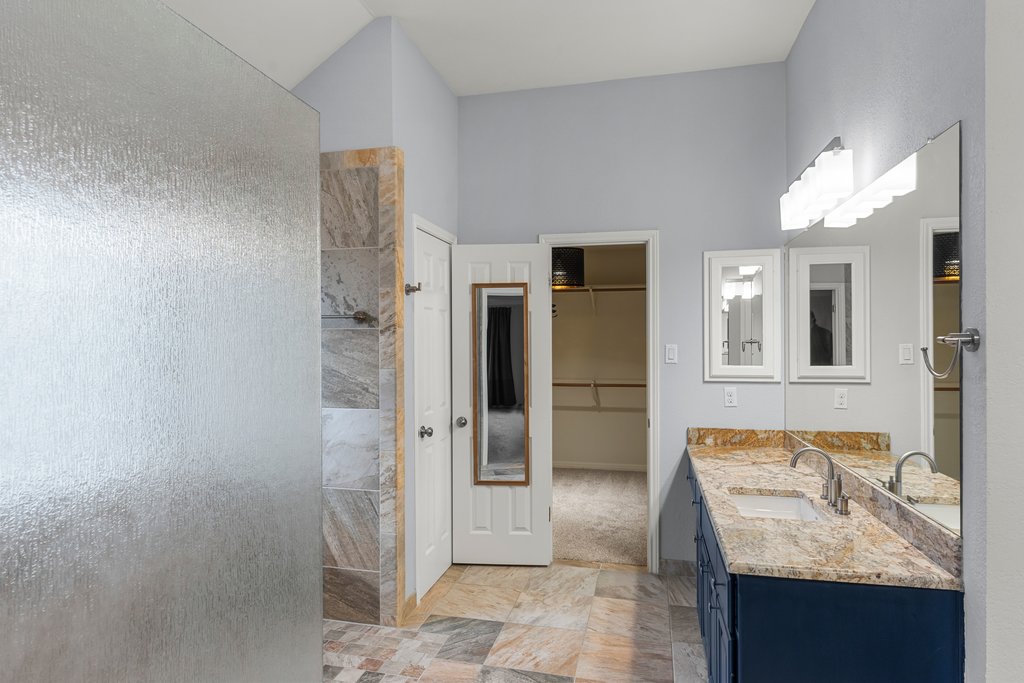 1406 Dapplegrey Lane Austin, TX 78727 - Photo 16 of 38 Bathroom featuring double vanity, a spacious closet, and walk in shower
