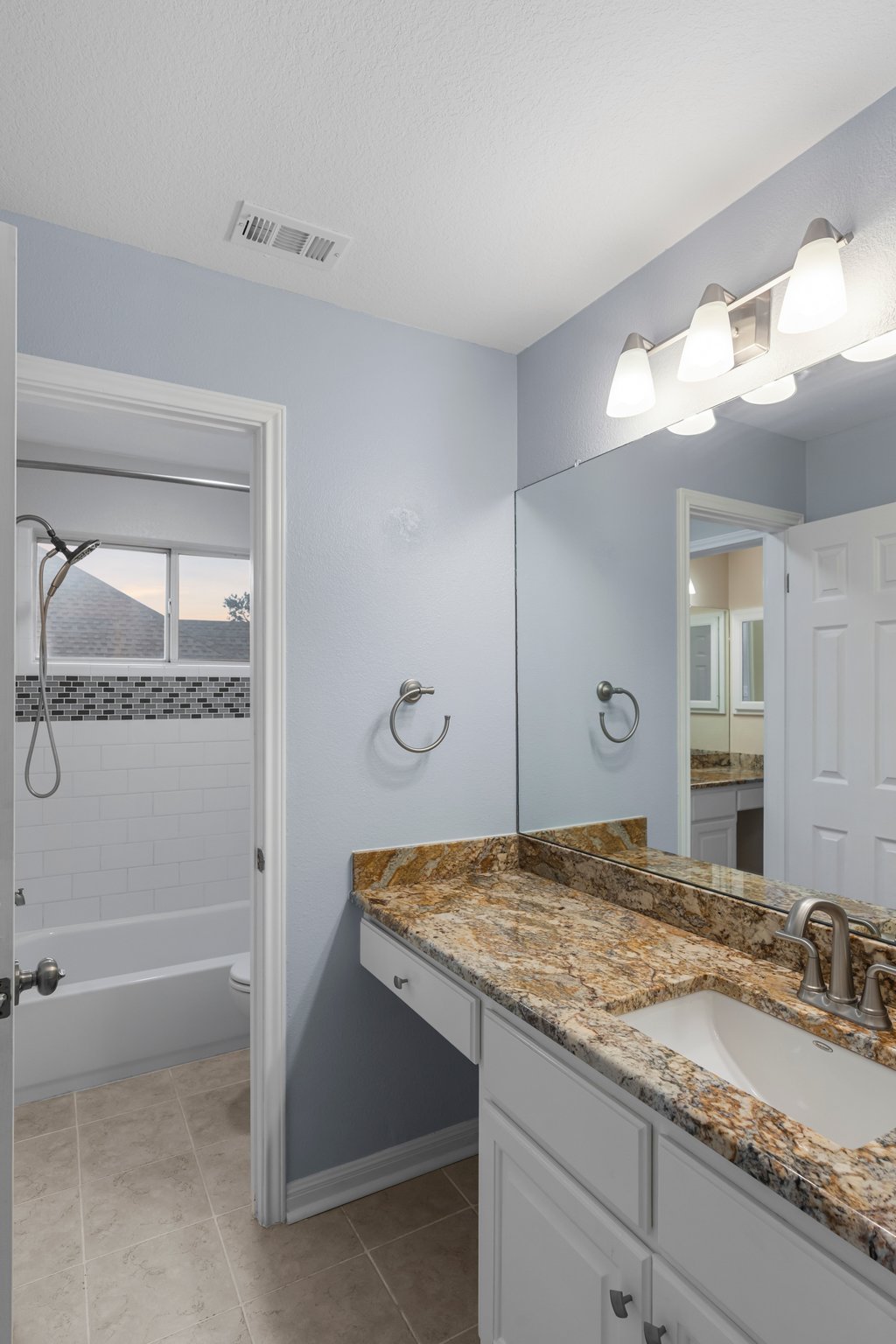 1406 Dapplegrey Lane Austin, TX 78727 - Photo 21 of 38 Bathroom with vanity, tub / shower combination, and light tile patterned floors
