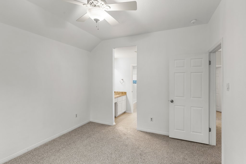 1406 Dapplegrey Lane Austin, TX 78727 - Photo 23 of 38 Unfurnished bedroom featuring light carpet, vaulted ceiling, connected bathroom, and a ceiling fan