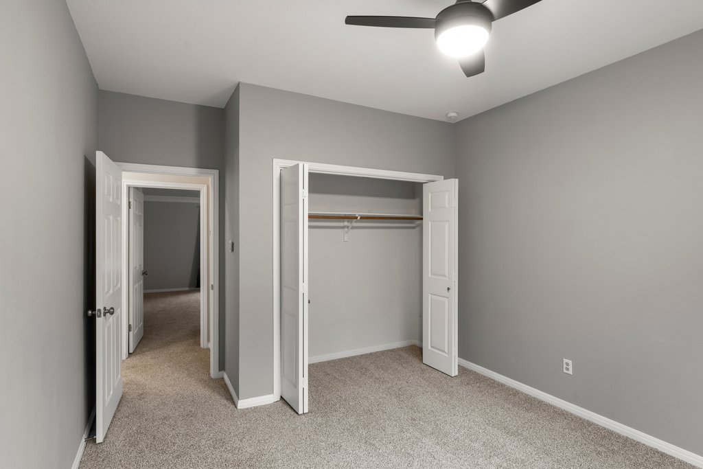 1406 Dapplegrey Lane Austin, TX 78727 - Photo 25 of 38 Unfurnished bedroom featuring light carpet, a closet, and a ceiling fan