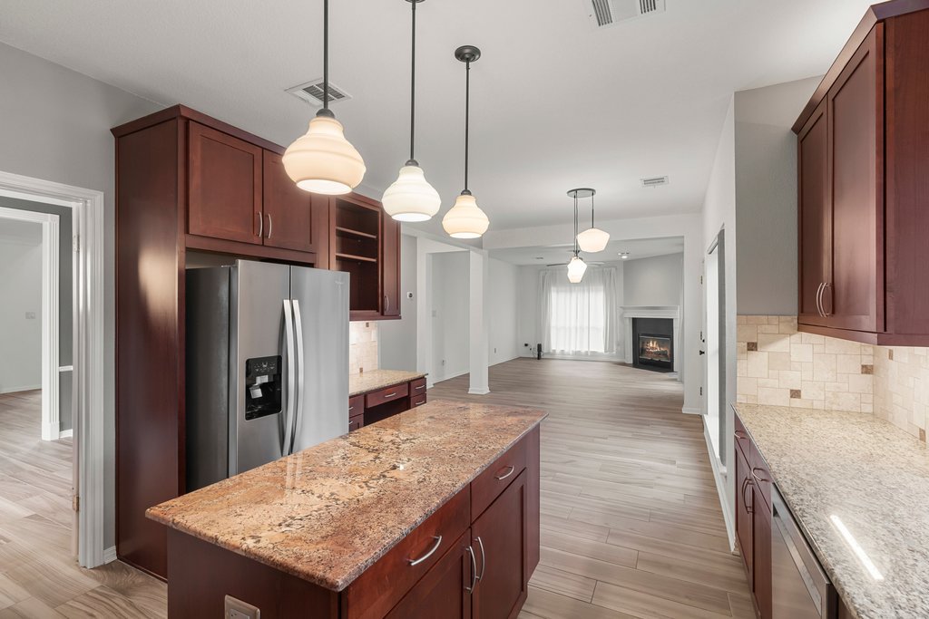 1406 Dapplegrey Lane Austin, TX 78727 - Photo 6 of 38 Kitchen with a kitchen island, stainless steel appliances, a lit fireplace, light wood finished floors, and pendant lighting
