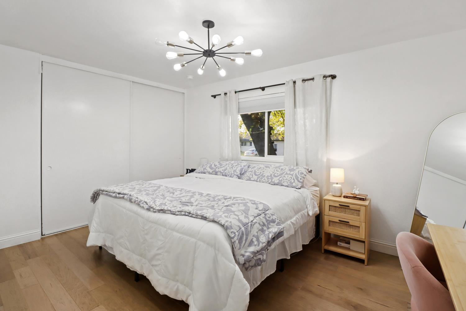 5208 Rambler Way Sacramento, CA 95841 - Photo 31 of 51 a bedroom with a bed a chandelier furniture and a flat tv screen