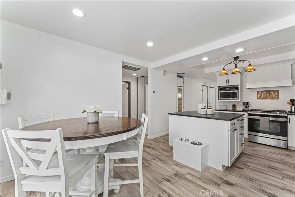 14456 Foothill, Unit 47 Sylmar, CA 91342 - Photo 12 of 26 a kitchen with stainless steel appliances kitchen island granite countertop a table chairs stove and white cabinets