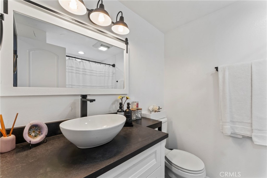 14456 Foothill, Unit 47 Sylmar, CA 91342 - Photo 17 of 26 a bathroom with a granite countertop sink a toilet and a mirror