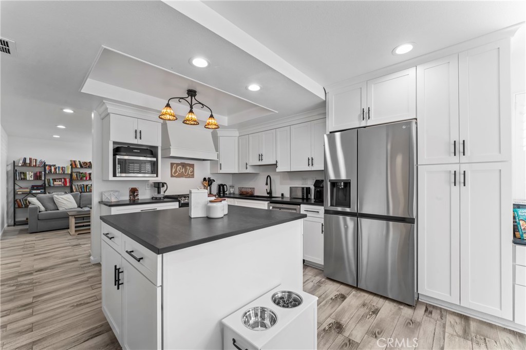 14456 Foothill, Unit 47 Sylmar, CA 91342 - Photo 2 of 26 a kitchen with a refrigerator a sink and a stove top oven with wooden floor