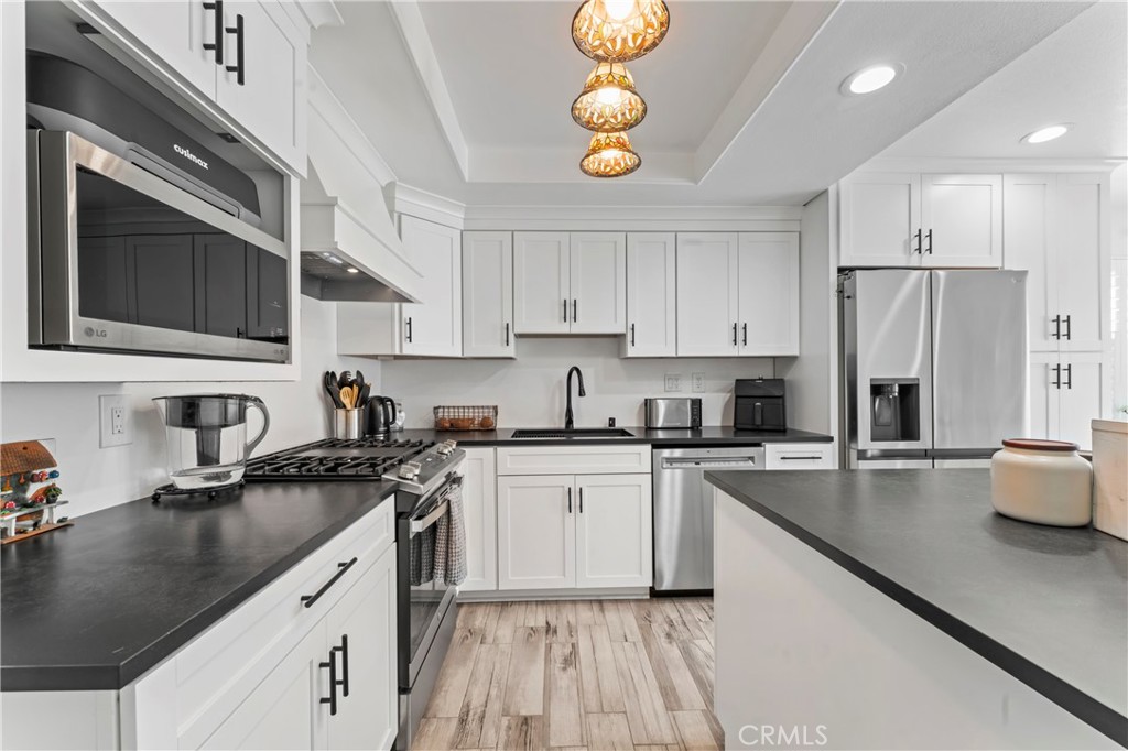 14456 Foothill, Unit 47 Sylmar, CA 91342 - Photo 8 of 26 a kitchen with stainless steel appliances granite countertop a sink stove microwave and refrigerator