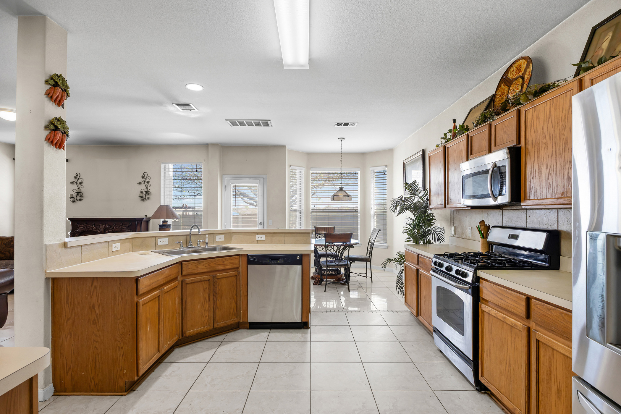 3502 Shiraz Loop Round Rock, TX 78665 - Photo 5 of 23 Kitchen with decorative backsplash, stainless steel appliances, light countertops, wood finish cabinetry, and light tile patterned floors