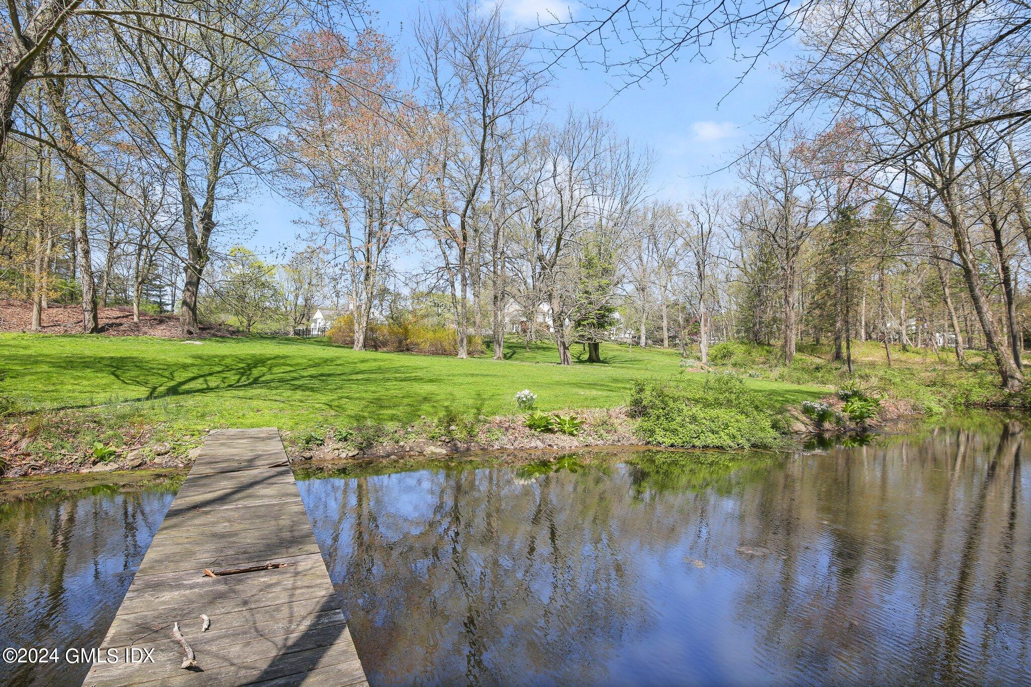 69 Clapboard Ridge Road Greenwich, CT 06830 - Photo 15 of 40 a view of a lake with a yard and large trees