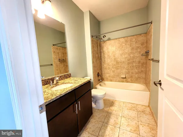 a bathroom with a granite countertop sink a toilet and shower