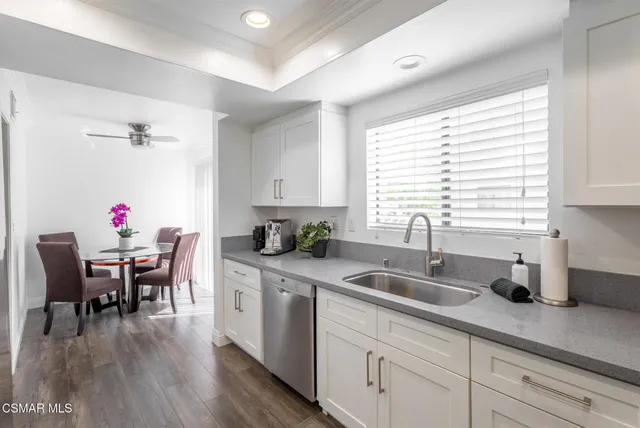 a kitchen with white cabinets sink dining table and chairs